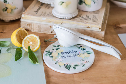 Lemon squeezer on a spoon holder with lemons and a book in the background