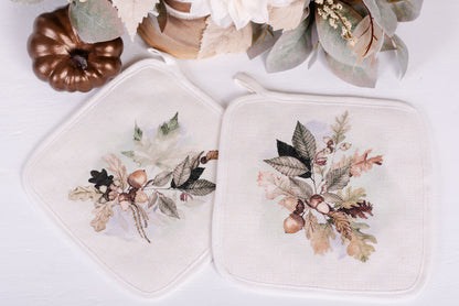 Set of two linen pot holders with watercolour acorn and leaf design styled with fall greenery