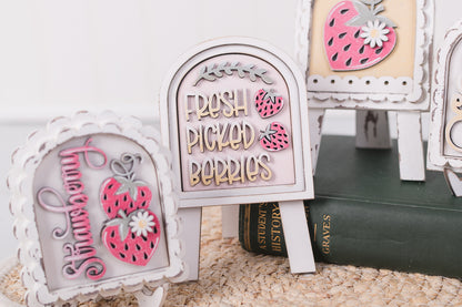 Decorative signs with text and berry designs on a textured surface.