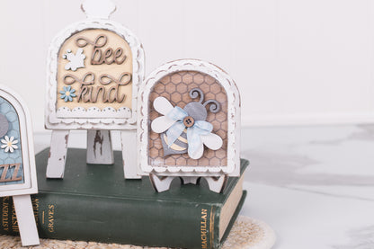 Decorative wooden signs with floral and bee designs on a white background