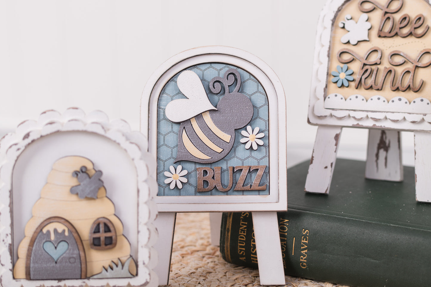 Decorative items including a bee-themed sign, a beehive, and a book on a white surface.