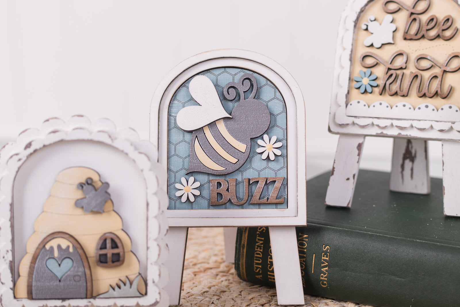 Decorative items including a bee-themed sign, a beehive, and a book on a white surface.