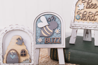 Decorative items including a bee-themed sign, a beehive, and a book on a white surface.