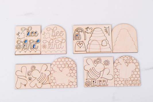 Set of wooden blanks with bee-themed designs on a white background