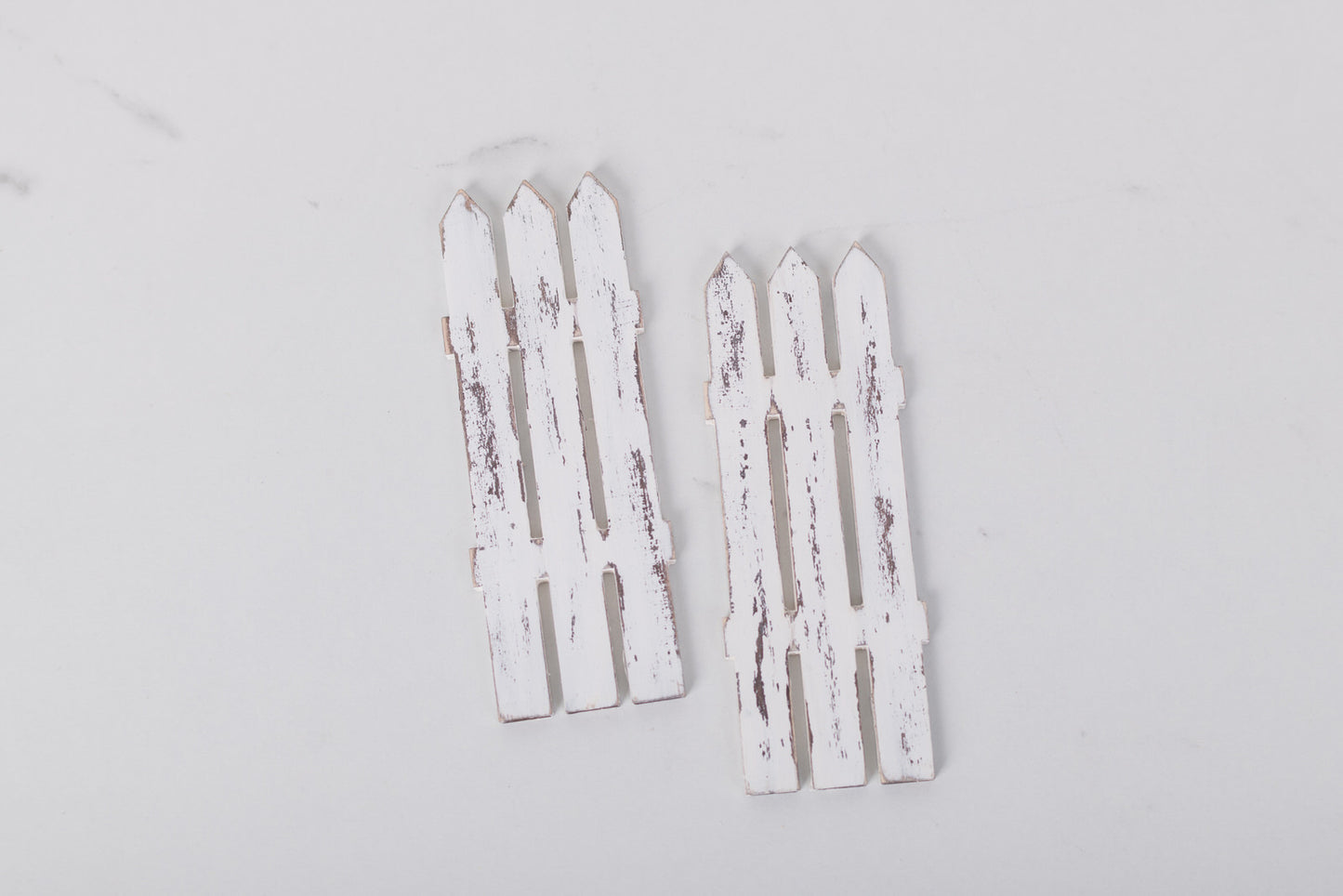 Two white picket fence decorations on a light gray background