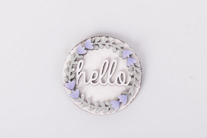 Decorative round sign with 'hello' text and purple lavender on a light gray background