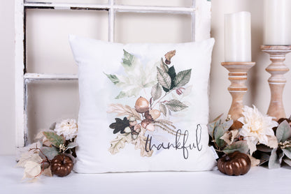 A hand-sewn, white velveteen pillow cover with a woodland acorns and leaves pattern, featuring an envelope style closure with a bronze snap detail.