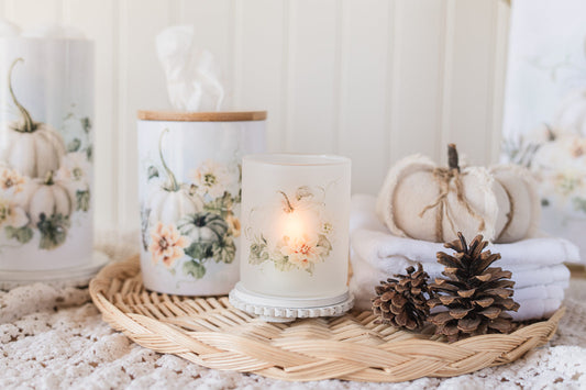 Cream pumpkin candle holder styled for bathroom fall decor on a woven tray with pumpkins and pinecones.