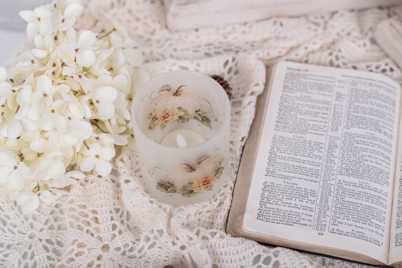 Open book, candle, and white flowers on a textured surface