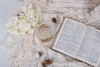Open book on a textured surface with flowers and a candle