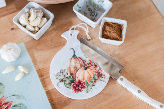 Ceramic spoon rest with warm orange pumpkins and fall florals on a butcher block