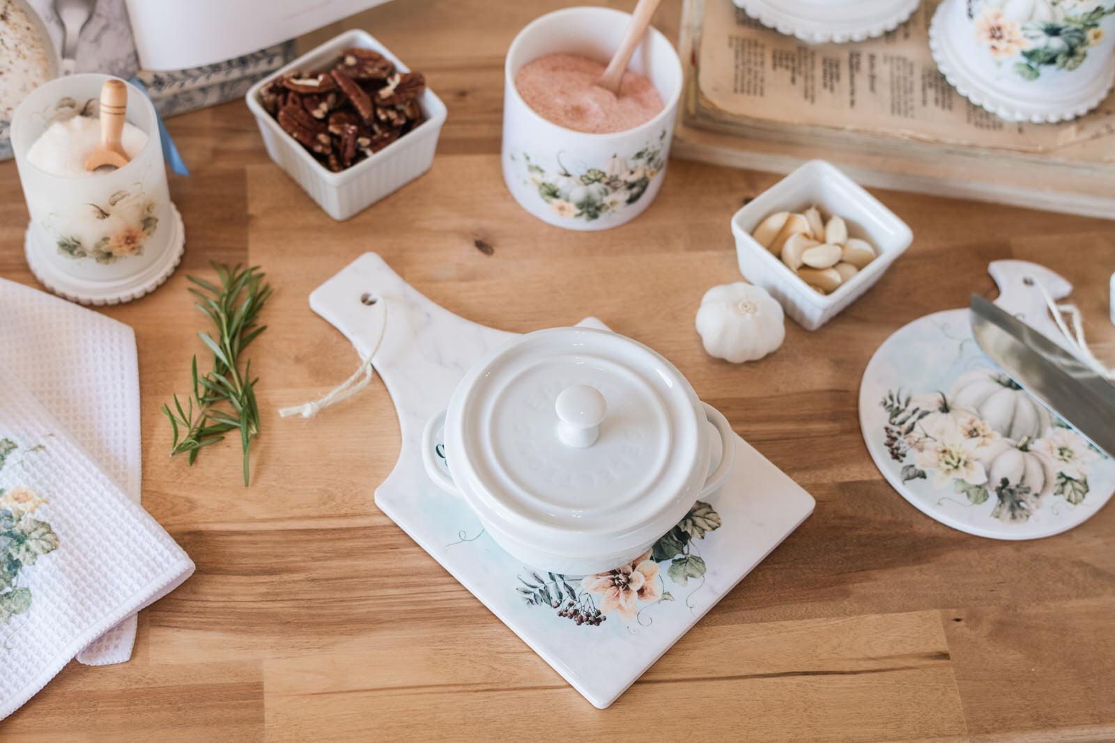 White ceramic pot with lid on a Autumn kitchen hot pad with scripture and neutral fall colors.