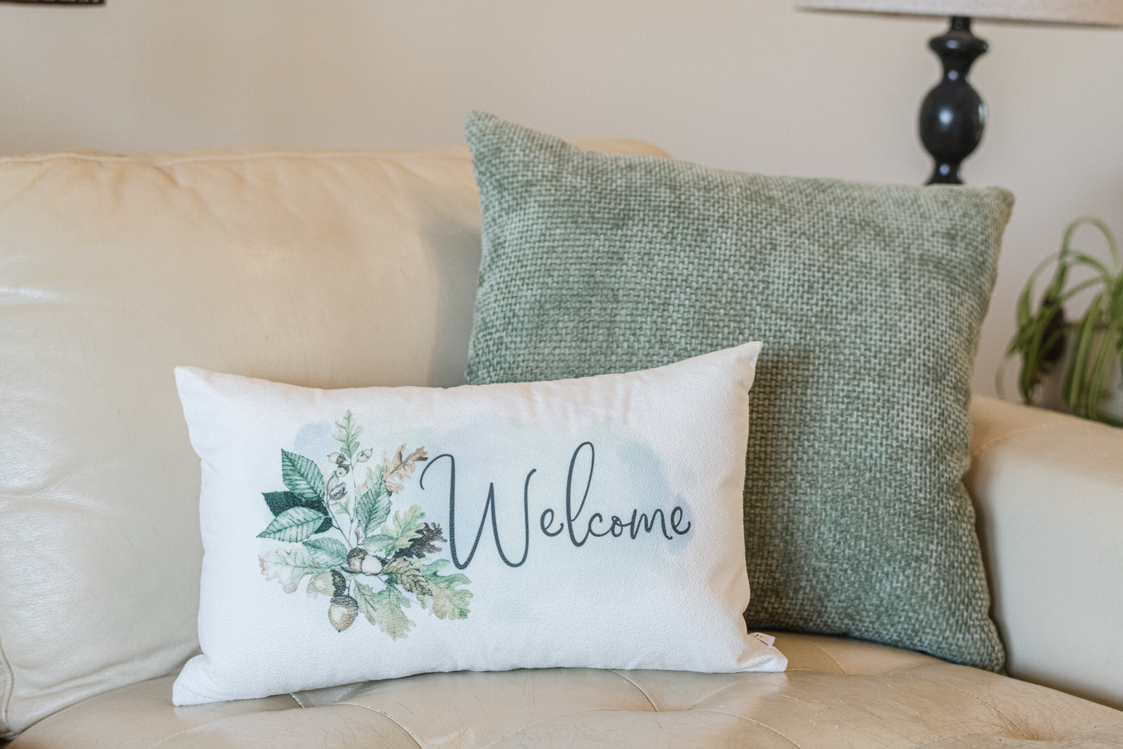 Decorative pillows on a couch with one featuring a 'Welcome' design.