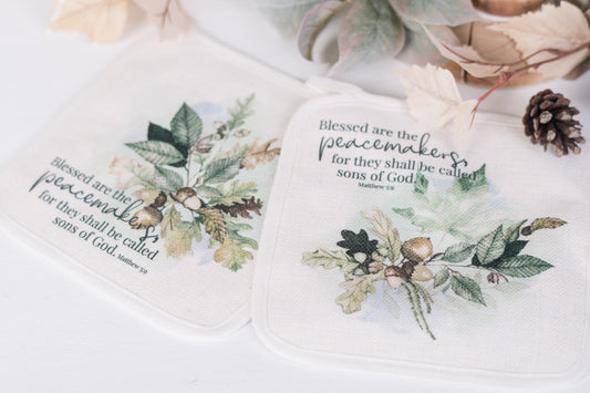 Two potholders with fall designs and Bible verse text on a white surface.