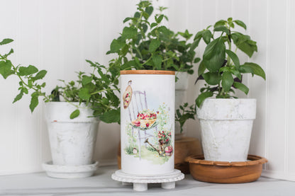 Decorative jar with a design surrounded by potted plants on a white surface