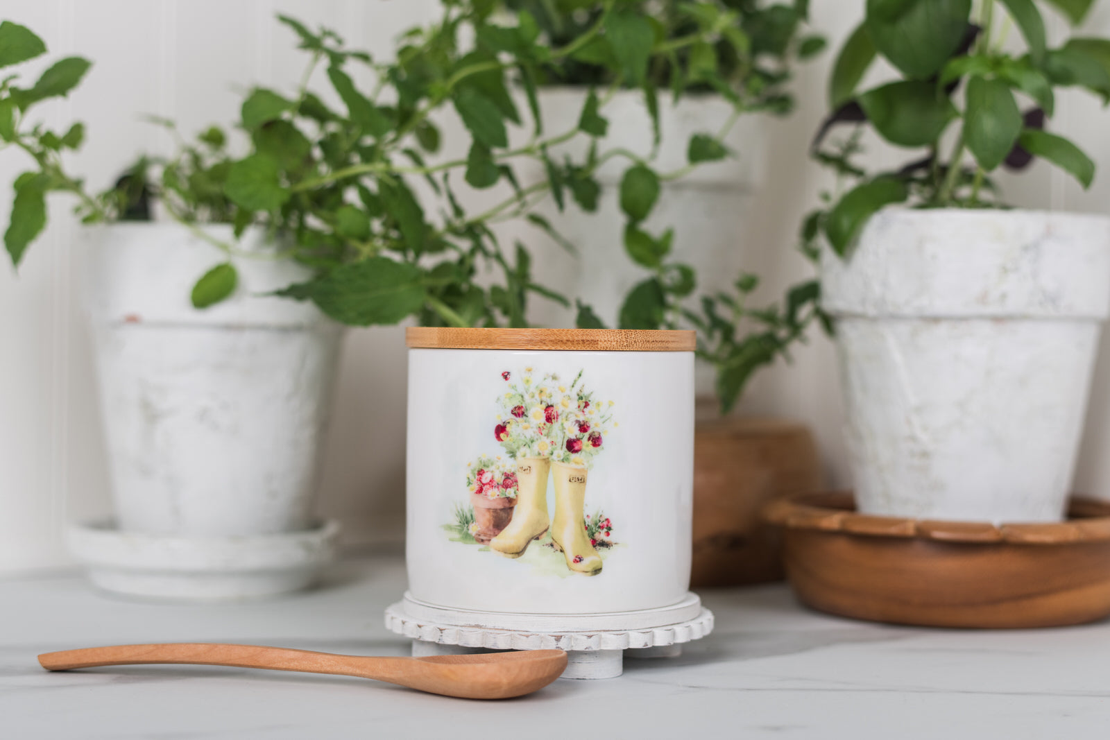 Jar with a design of boots and flowers on a white surface with plants in the background