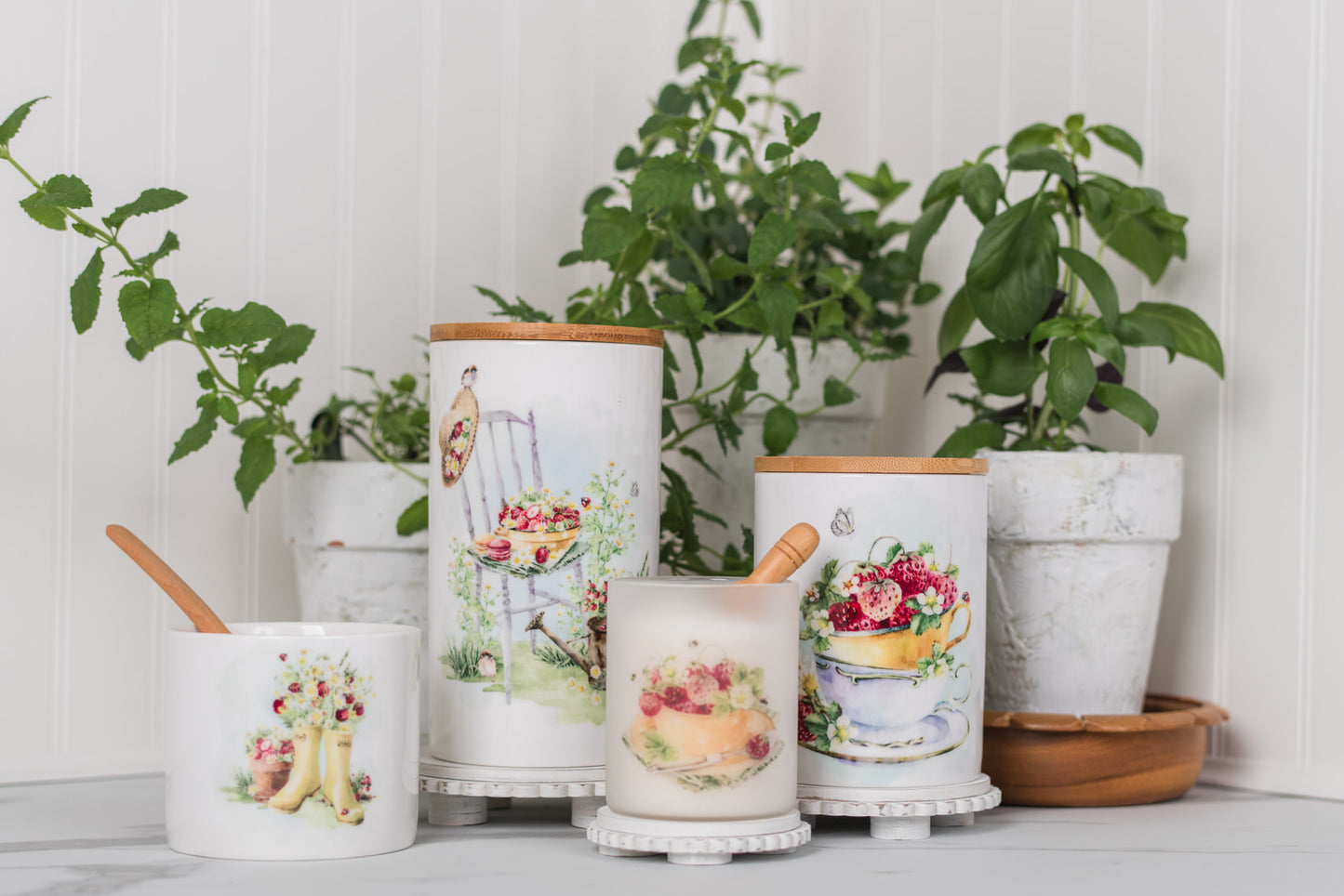 Set of ceramic canisters with decorative designs on a white surface with plants in the background