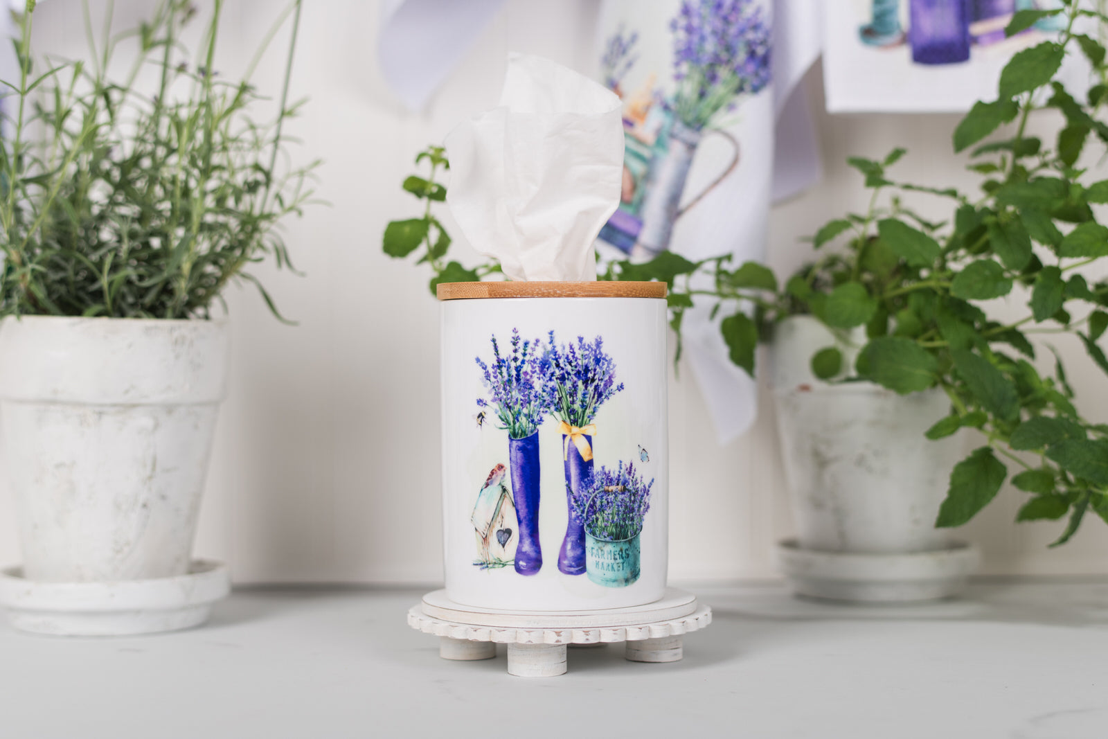 Decorative tissue holder with floral design on a surface with plants in the background