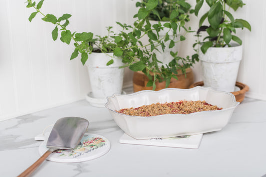 White dish with crumble on a table with a trivet underneath 