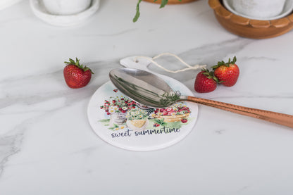 Round trivet with strawberry art on a summer dining table.