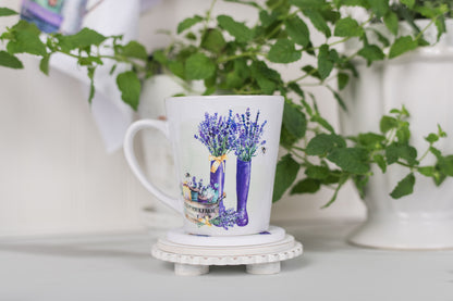 Mug with lavender design on a white surface with greenery in the background