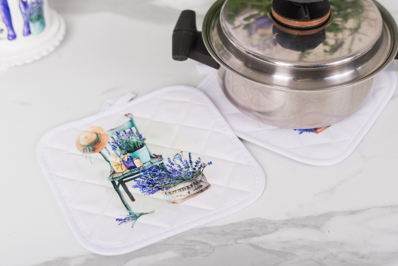 potholder with a floral design on a white surface next to a metal pot.