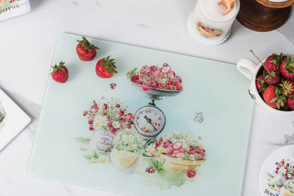 Decorative glass cutting board with floral and fruit design on a white surface