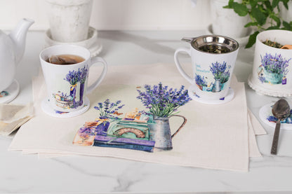 Mugs with floral designs on a table with a teapot and saucer.