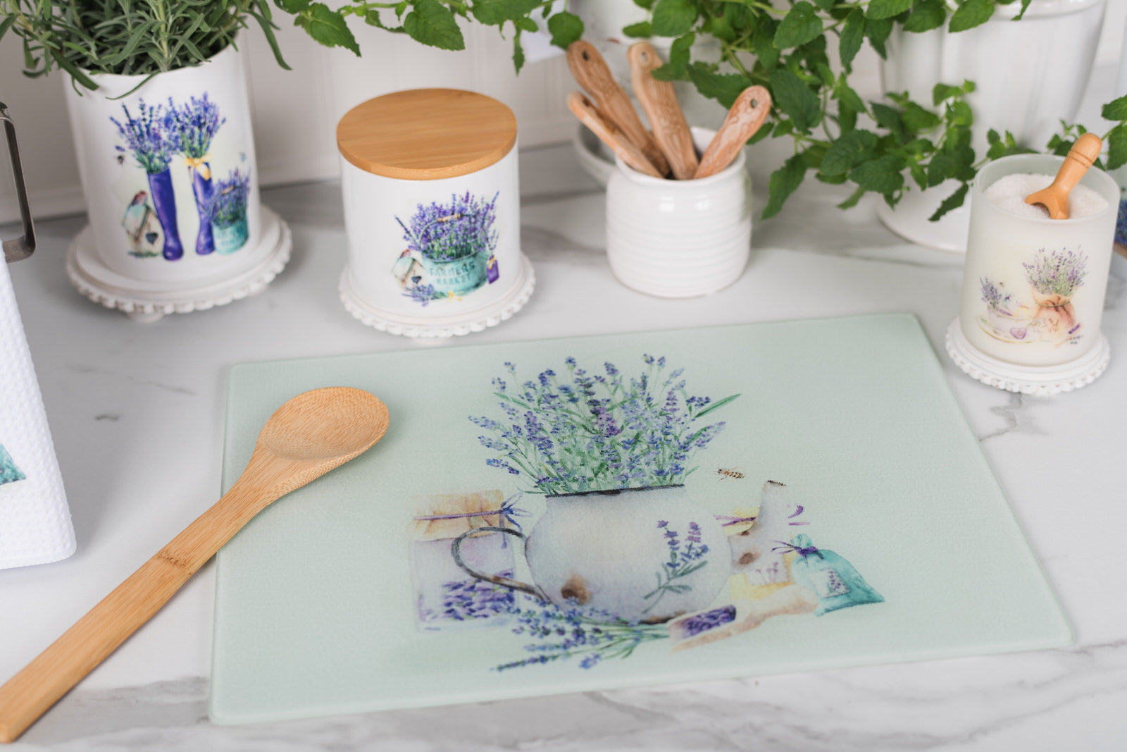Decorative cutting board with floral design on a table with kitchen items.