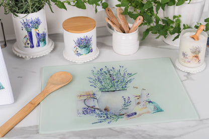 Decorative cutting board with floral design on a table with kitchen items.