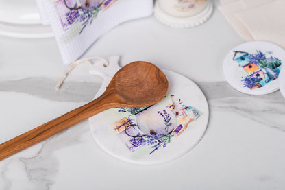 Wooden spoon on a coaster with floral design on a marble surface