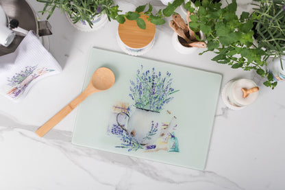 Decorative cutting board with floral design on a table with kitchen items.