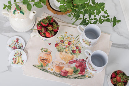 Decorative placemat with floral and food illustrations, surrounded by mugs, strawberries, and a teapot.