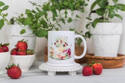 Mug with a floral and fruit design on a white surface with strawberries and plants in the background