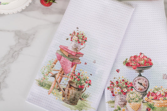 Two towels with floral and fruit designs on a marble surface