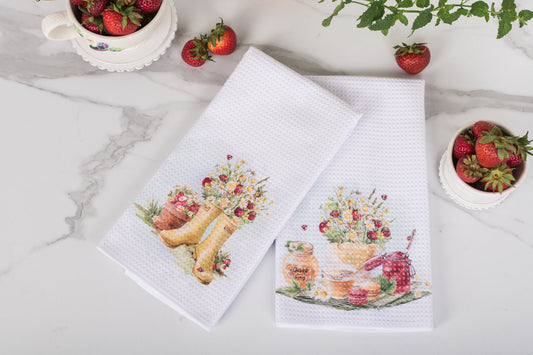 Two decorative towels with floral and food-themed designs on a marble surface with strawberries.