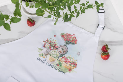 White apron with floral design and 'sweet summertime' text, surrounded by strawberries and a plant.