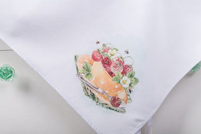 corner of apron with a cake and fruit design on a white surface.