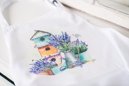 Flat-lay of adult apron with birdhouse and lavender design 